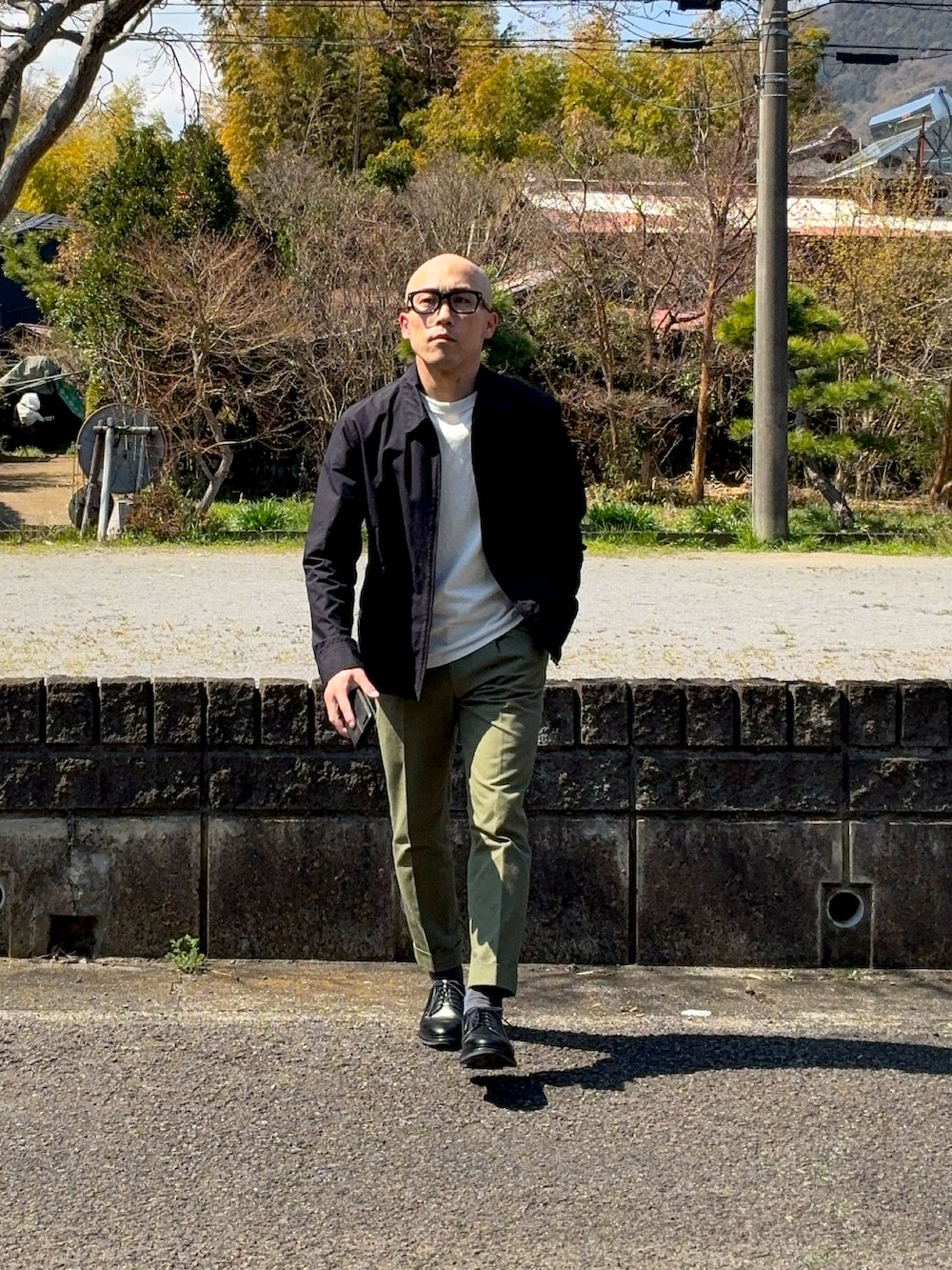 ブラック系のドレスシューズ、グリーン系のスラックス、ブラック系のブルゾンを着用したメンズの春コーディネートの4枚目の写真