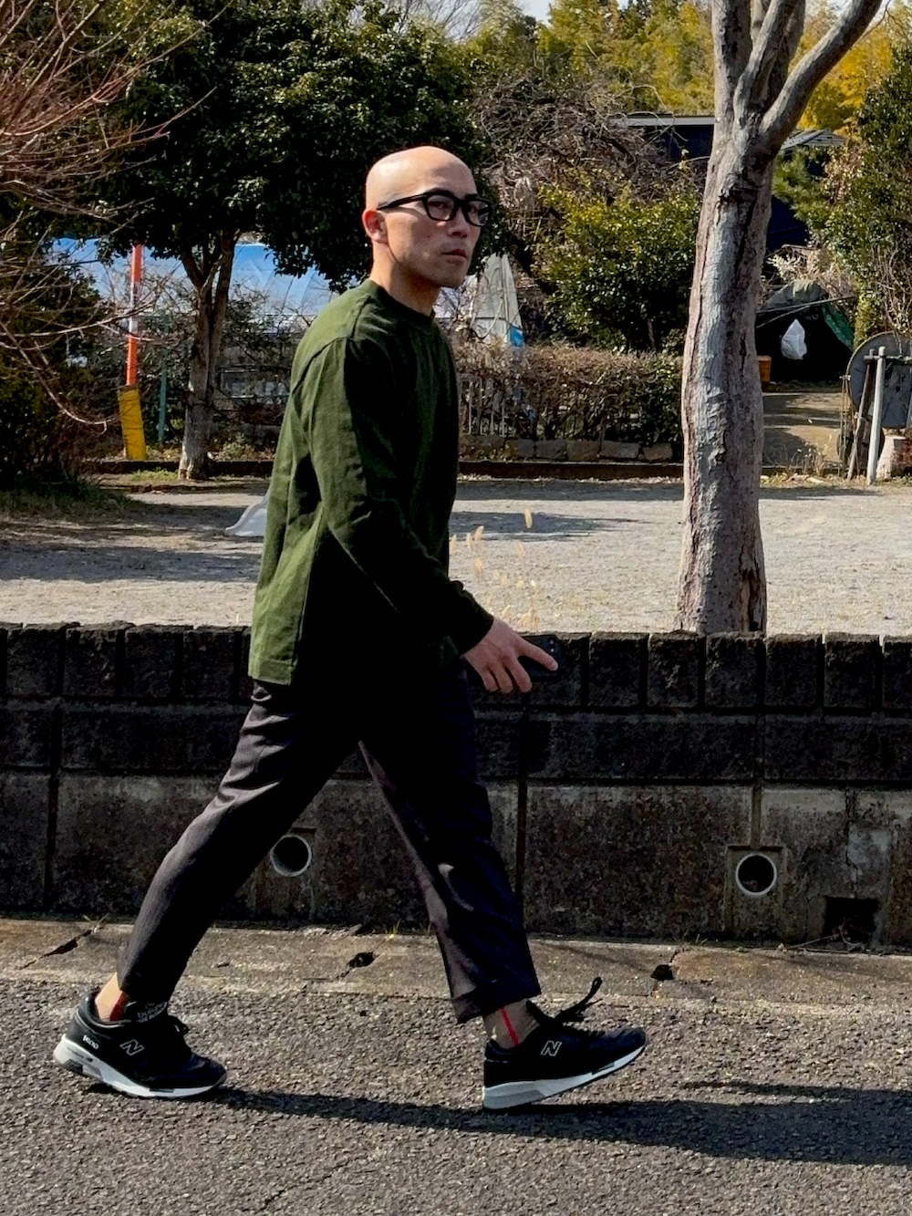 グリーン系のTシャツ/カットソー、ブラック系のスニーカー、ブラック系のメガネを着用したメンズの冬コーディネートの2枚目の写真