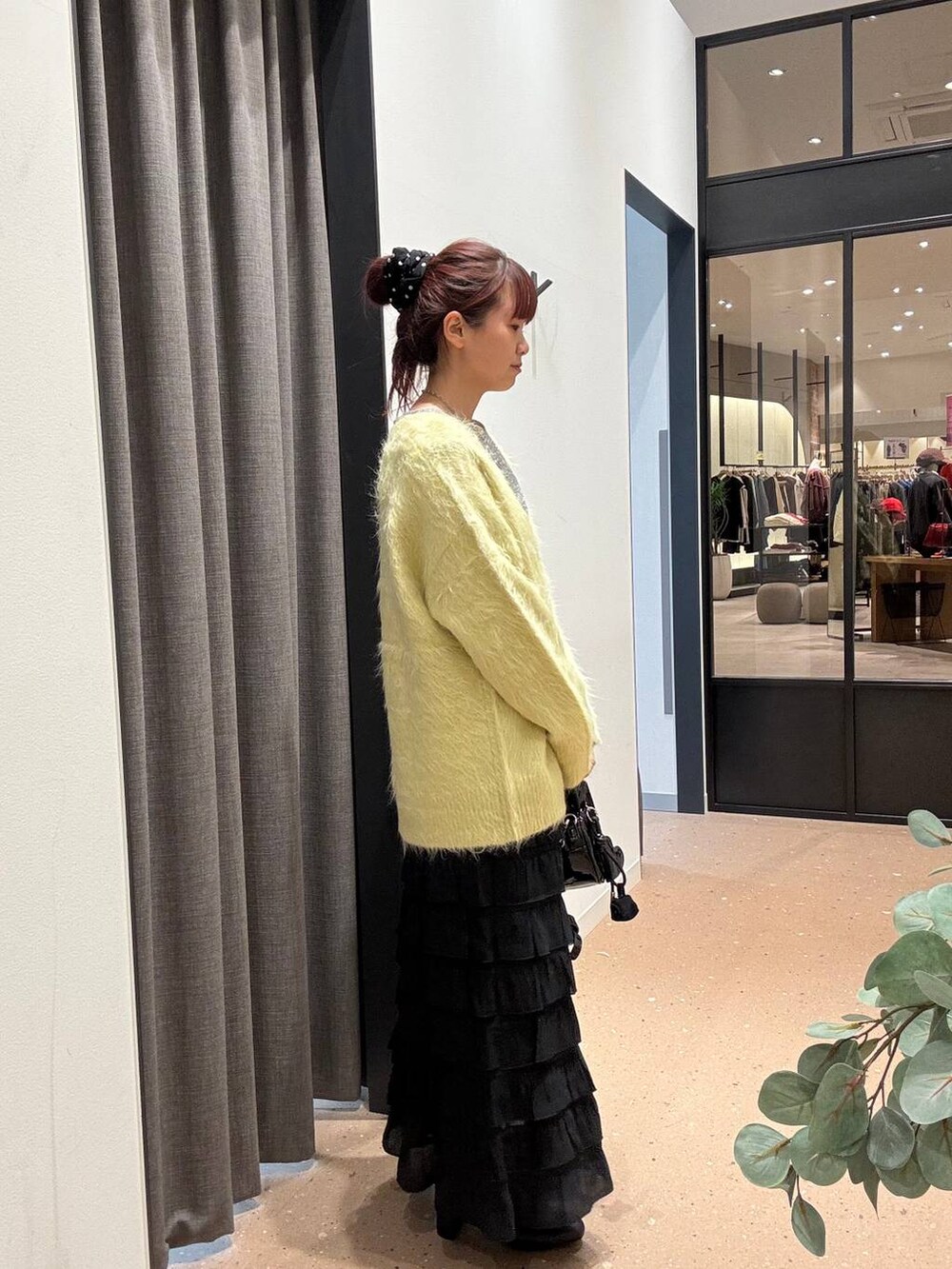 ブラック系のスカート、ブラック系のブーツ、イエロー系のカーディガン/ボレロを着用したレディースの秋コーディネートの2枚目の写真