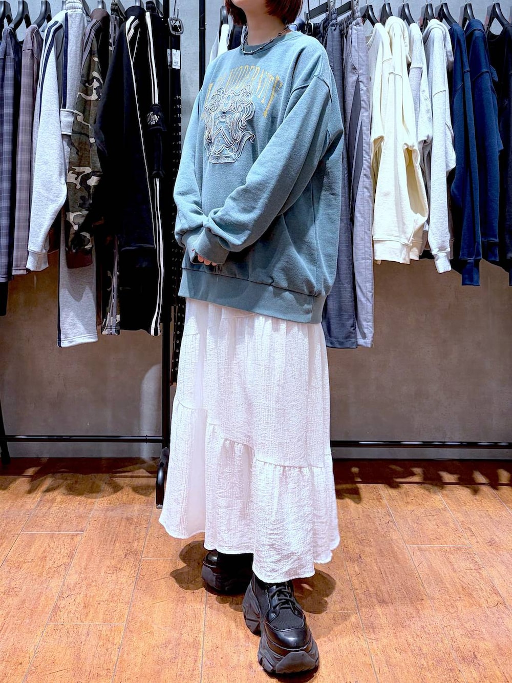 ブラック系のブーツ、グリーン系のスウェット、ホワイト系のスカートを着用したレディースの春コーディネートの2枚目の写真