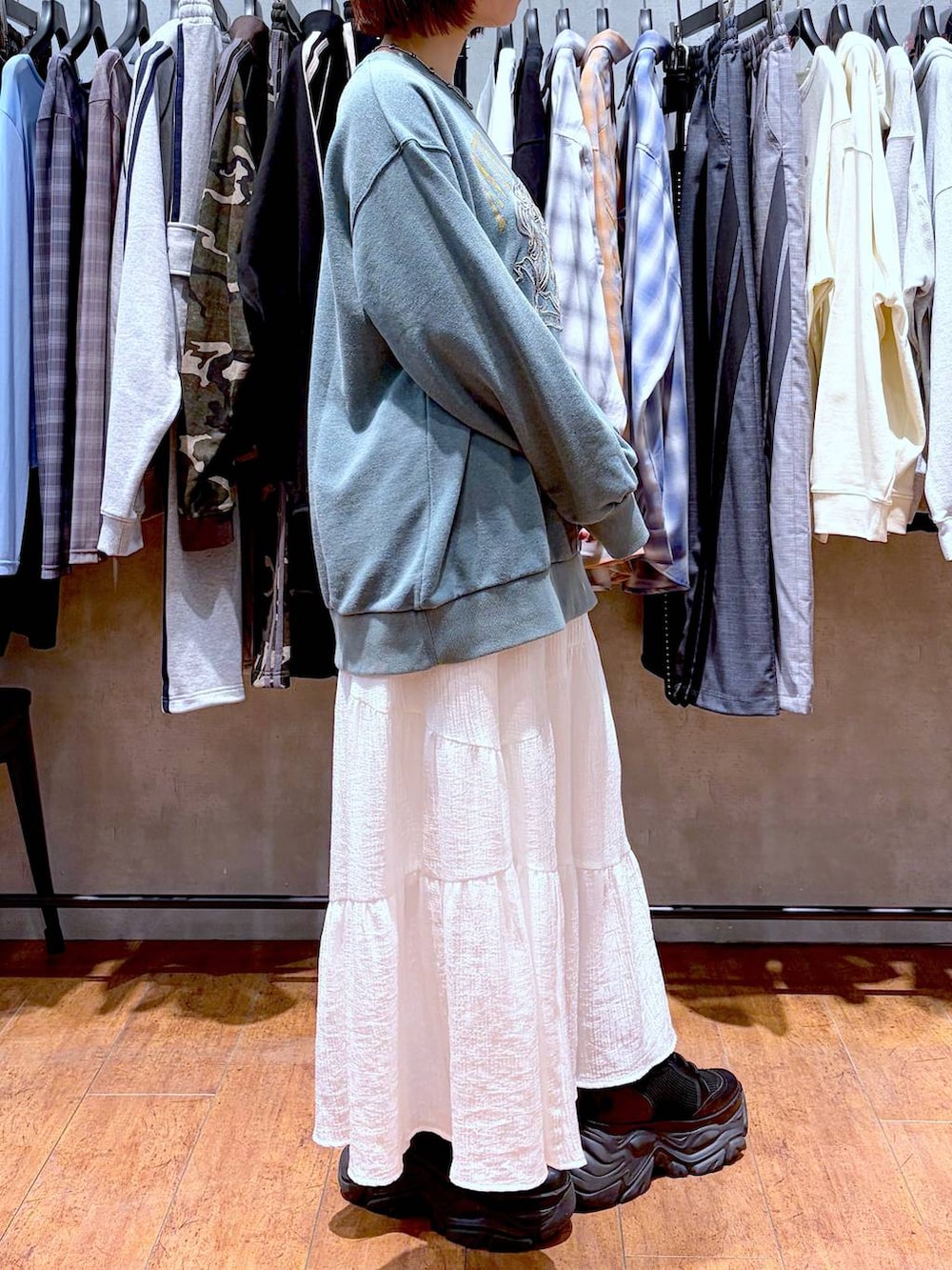 ブラック系のブーツ、グリーン系のスウェット、ホワイト系のスカートを着用したレディースの春コーディネートの6枚目の写真