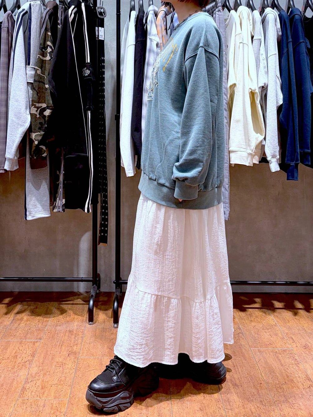 ブラック系のブーツ、グリーン系のスウェット、ホワイト系のスカートを着用したレディースの春コーディネートの3枚目の写真