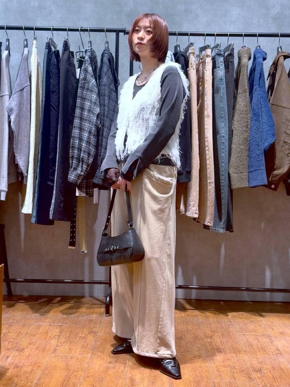 ブラック系のハンドバッグ、ブラウン系のスウェットパンツ、ブラック系のサンダルを着用したレディースの冬コーディネートの2枚目の写真