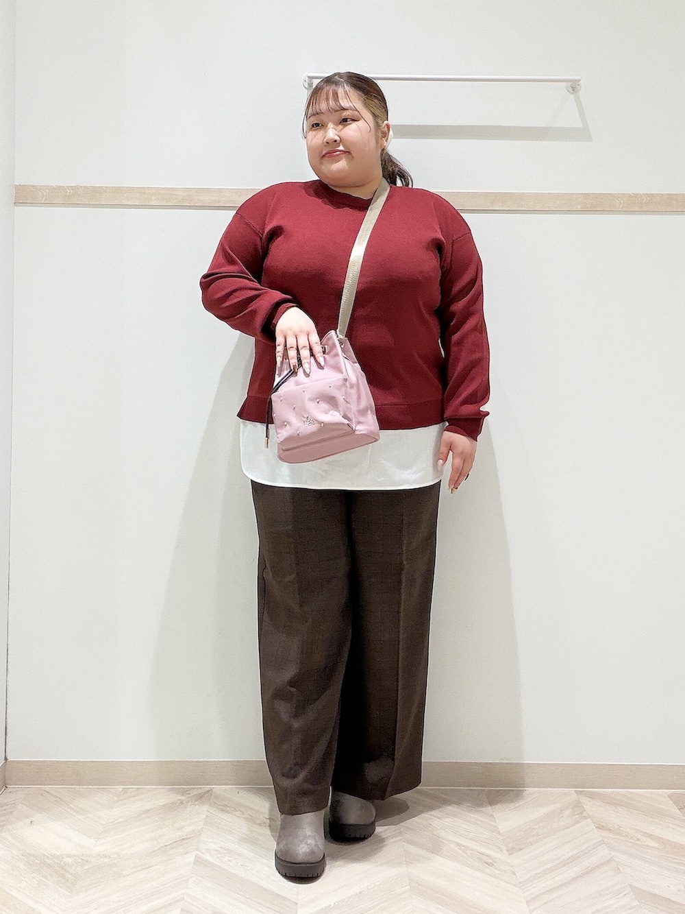 レッド系のニット/セーター、ブラウン系のその他パンツ、ブラウン系のブーツを着用したレディースの秋コーディネートの2枚目の写真