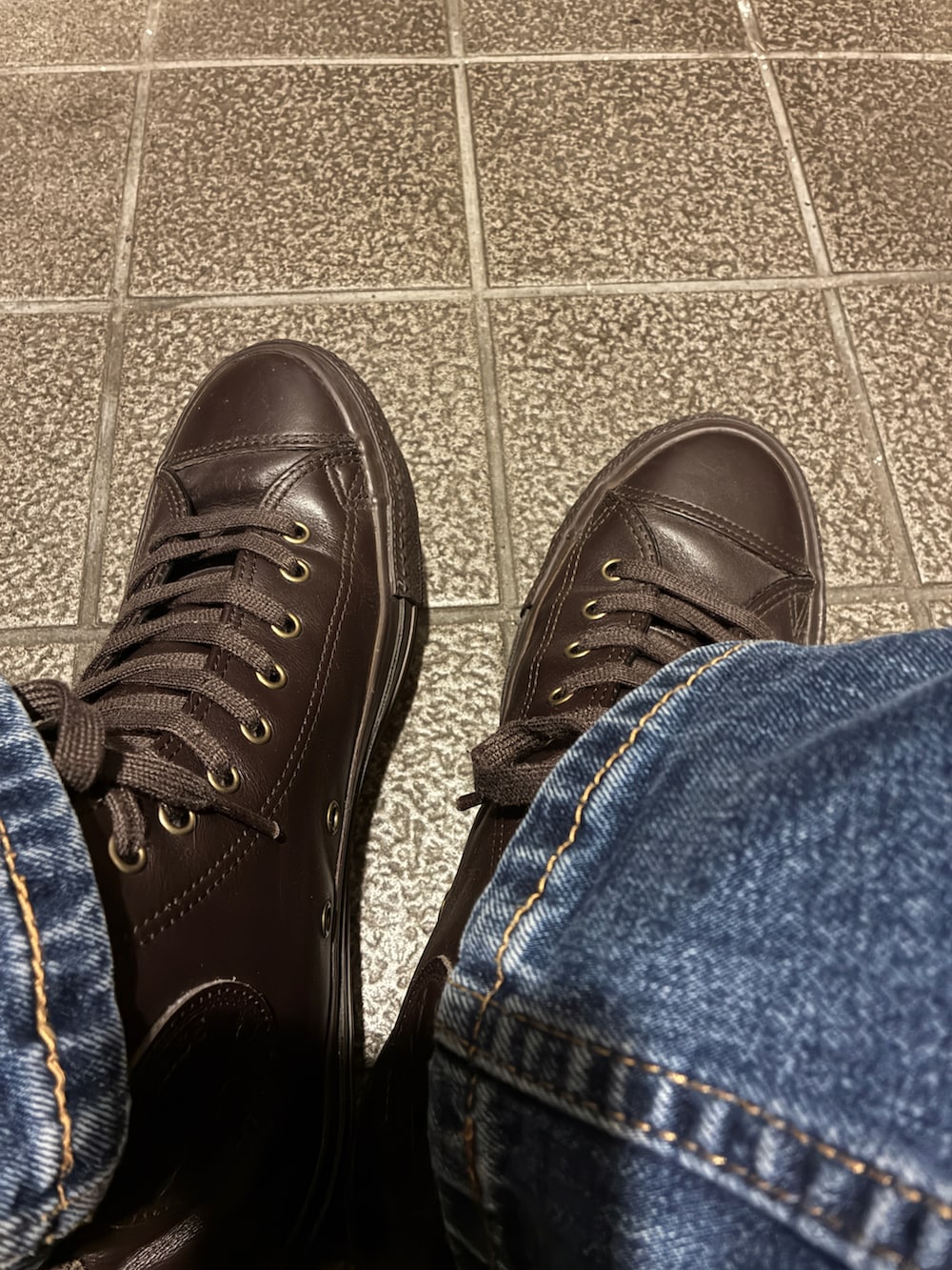 ブラウン系のトレンチコート、グレー系のパーカー、ブルー系のデニムパンツを着用したメンズの冬コーディネートの3枚目の写真