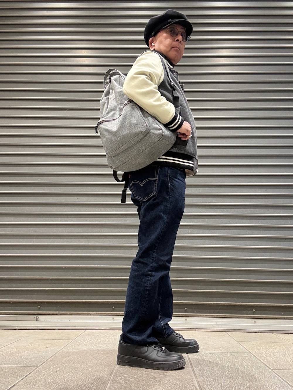 グレー系のスタジャン、ホワイト系のTシャツ/カットソー、ブルー系のデニムパンツを着用したメンズの秋コーディネートの2枚目の写真