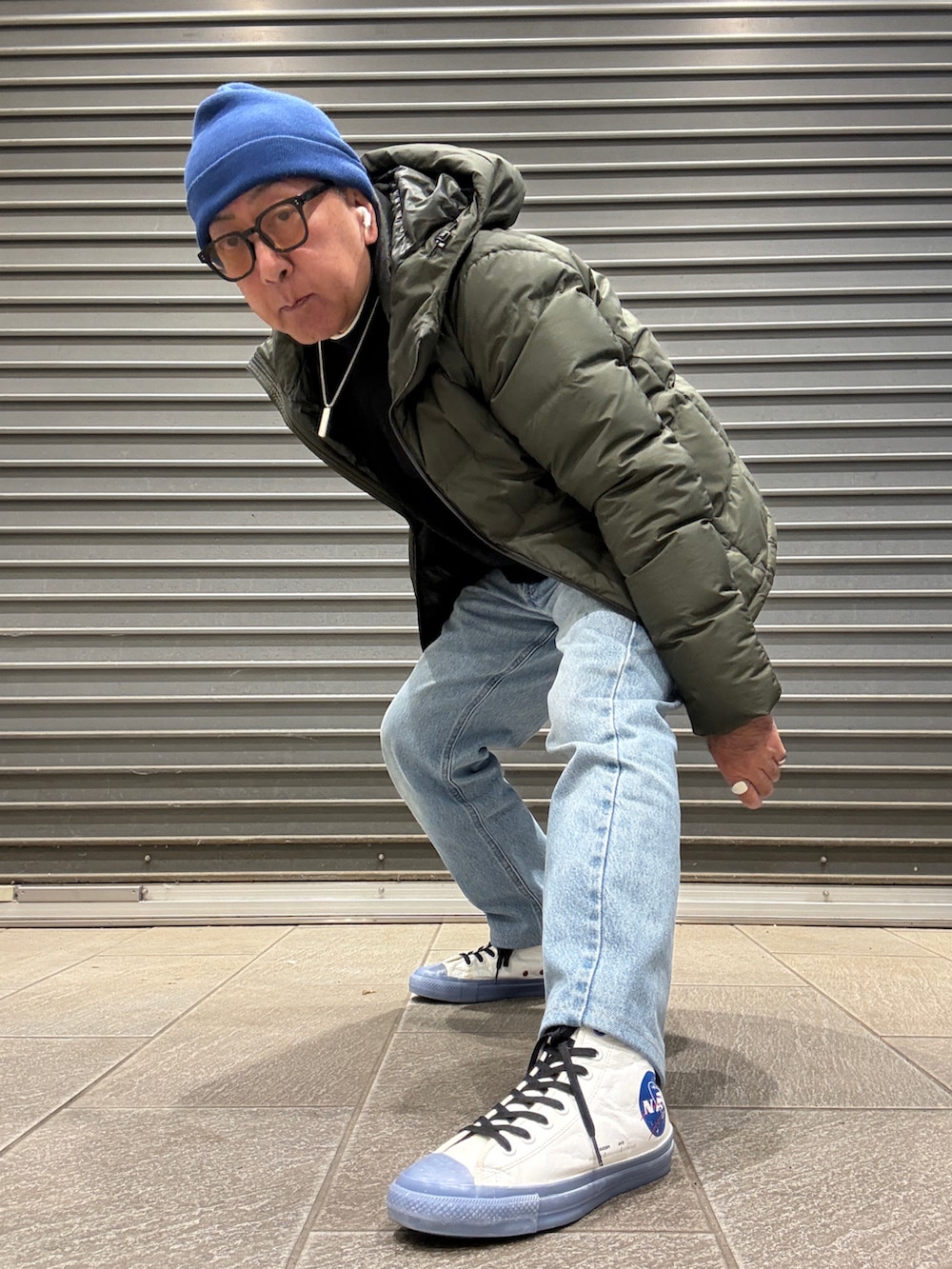 ブラック系のニット/セーター、グリーン系のダウンジャケット/コート、ホワイト系のTシャツ/カットソーを着用したメンズの冬コーディネートの2枚目の写真