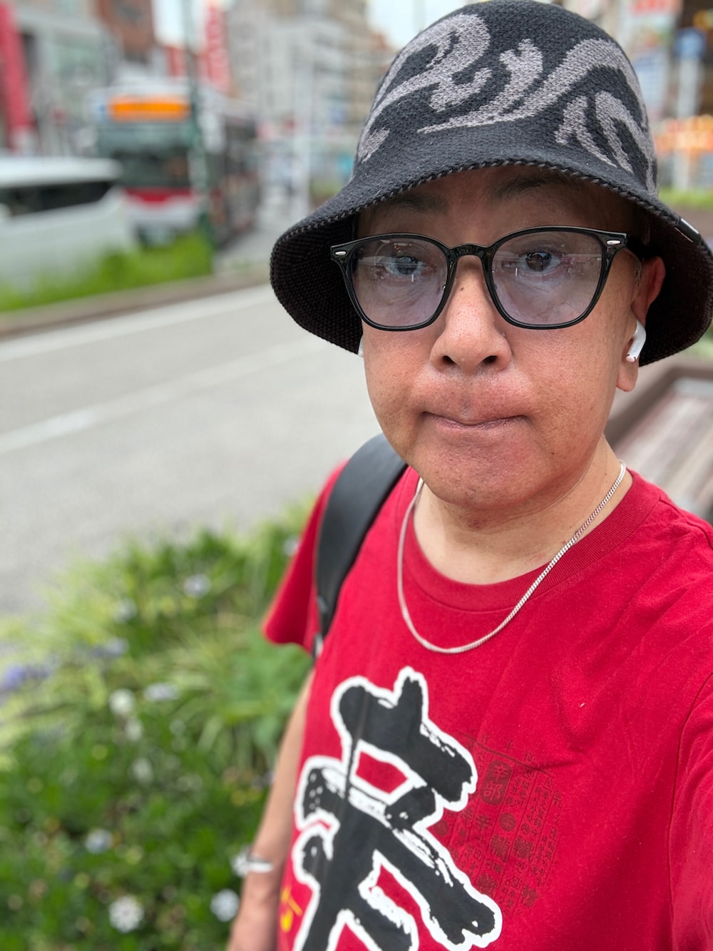 ブルー系のデニムパンツ、レッド系のTシャツ/カットソー、ブラウン系のドレスシューズを着用したメンズの夏コーディネートの2枚目の写真