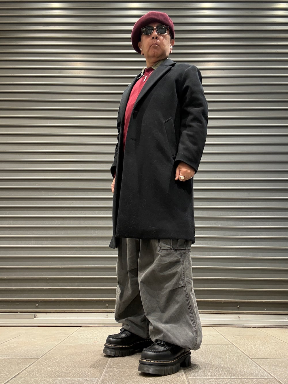 ブラック系のローファー、レッド系のスウェット、ブラック系のチェスターコートを着用したメンズの冬コーディネートの2枚目の写真