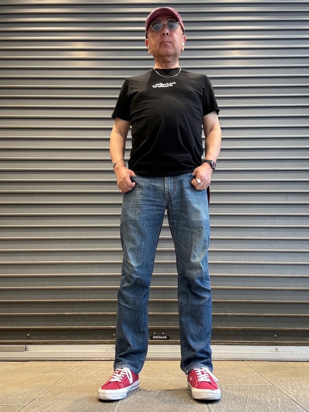 ブルー系のデニムパンツ、ブラック系のTシャツ/カットソー、レッド系のスニーカーを着用したメンズの春コーディネートの2枚目の写真