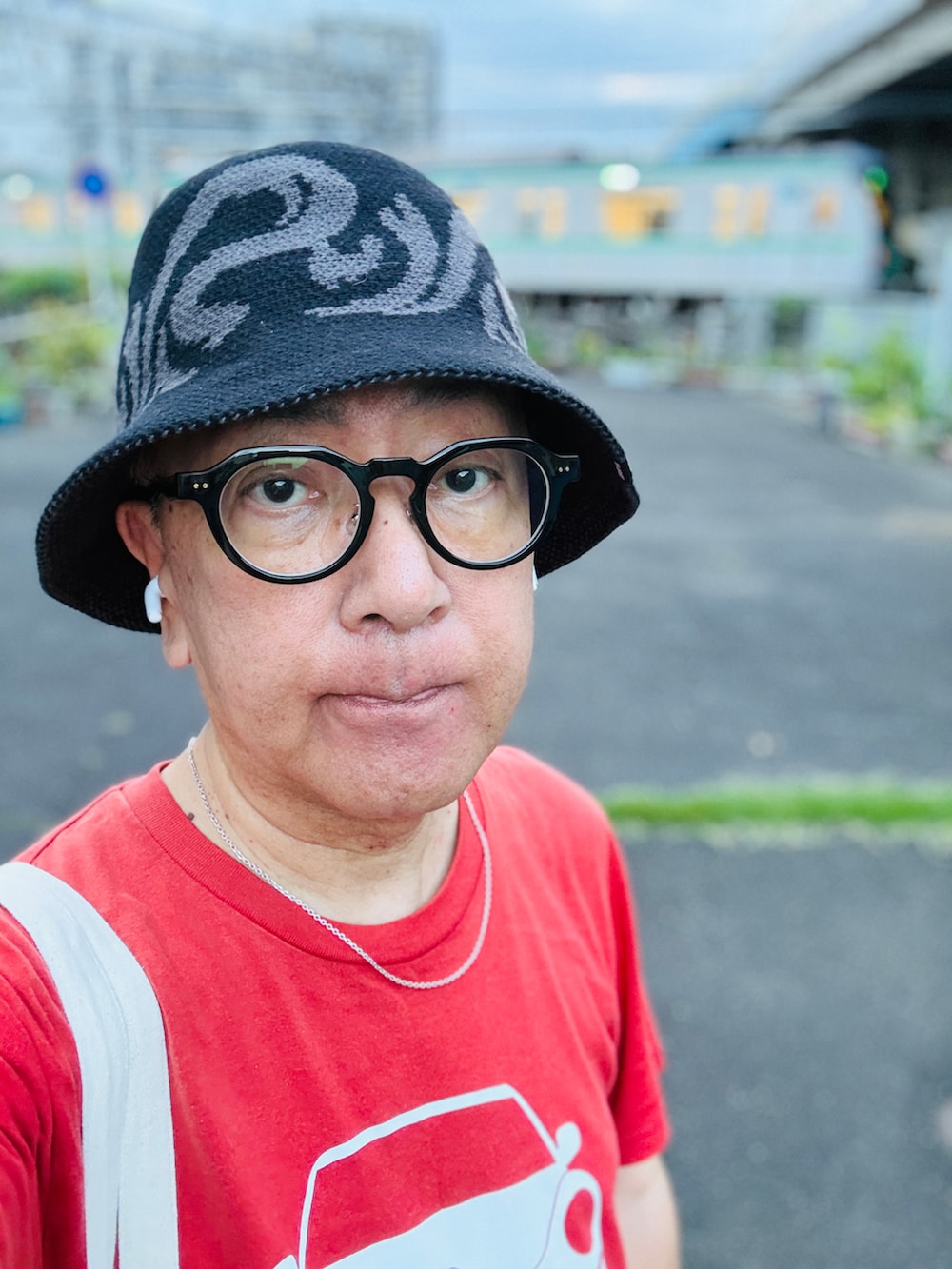 ブルー系のデニムパンツ、レッド系のTシャツ/カットソー、ホワイト系のトートバッグを着用したメンズの夏コーディネートの2枚目の写真