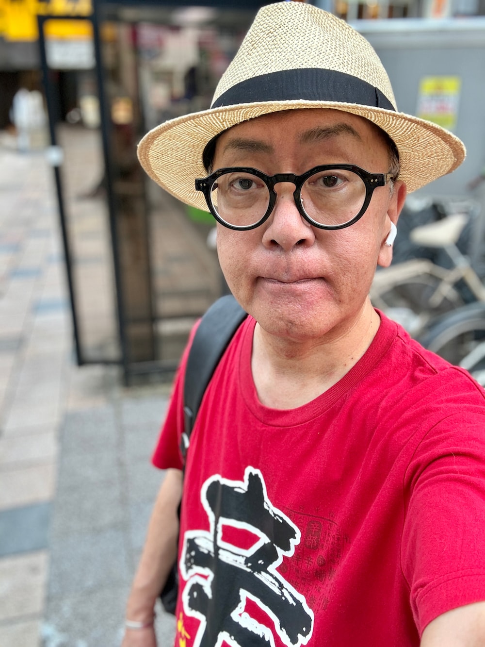 ブルー系のデニムパンツ、レッド系のTシャツ/カットソー、ブラック系のバックパック/リュックを着用したメンズの夏コーディネートの2枚目の写真