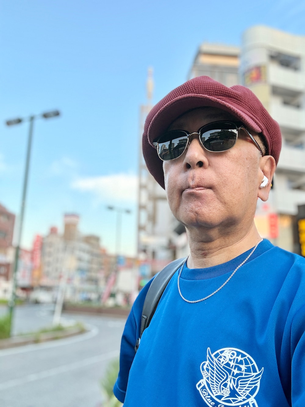 レッド系のスニーカー、ブルー系のTシャツ/カットソー、グレー系のカーゴパンツを着用したメンズの夏コーディネートの2枚目の写真