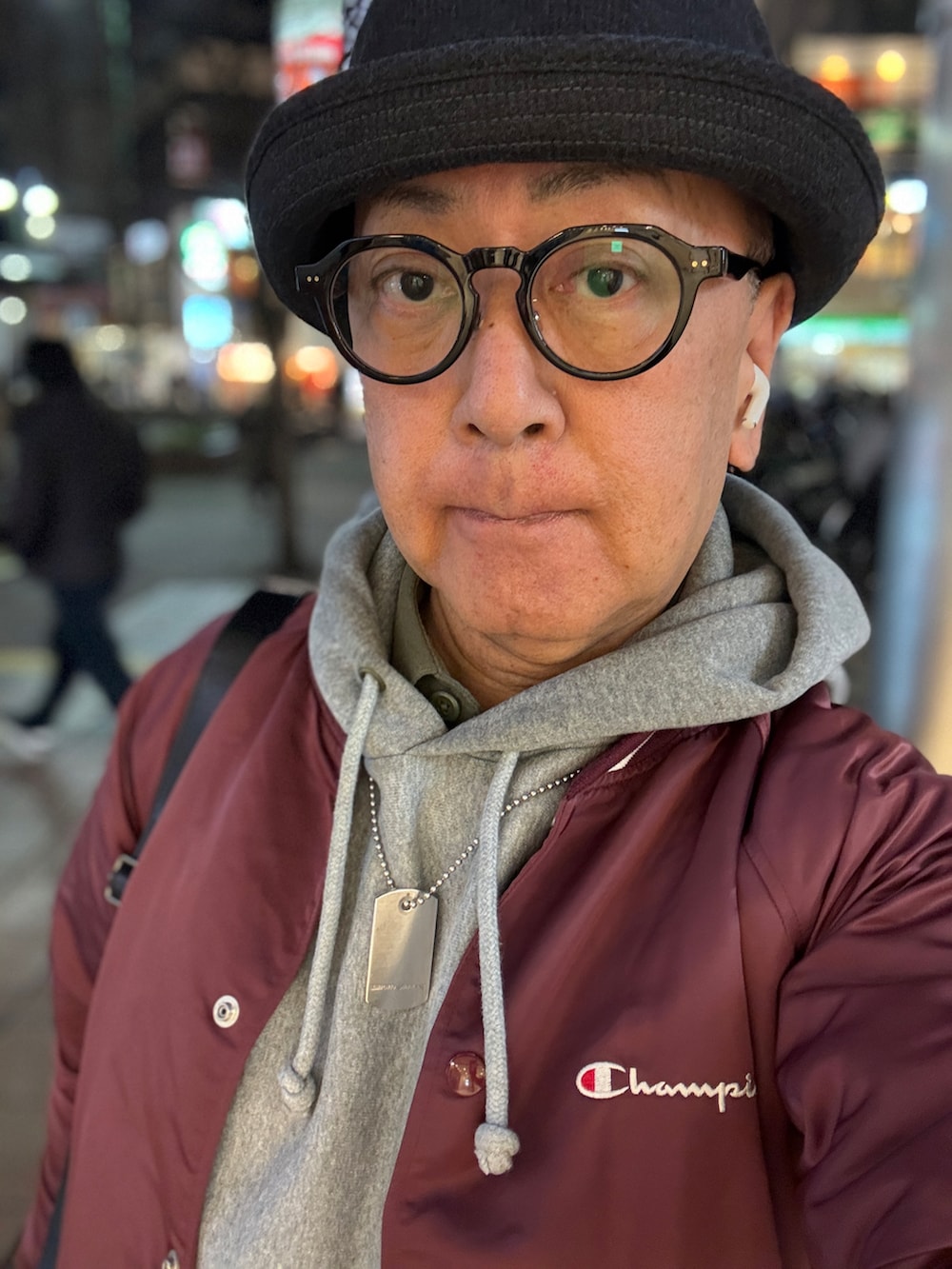 グレー系のパーカー、レッド系のナイロンジャケット、ブラック系のショルダーバッグを着用したメンズの冬コーディネートの3枚目の写真