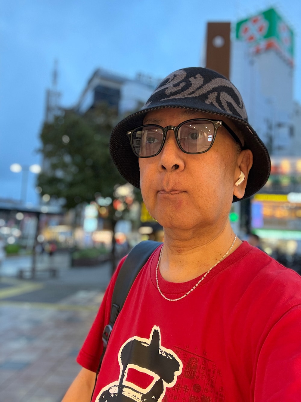 レッド系のTシャツ/カットソー、ブルー系のデニムパンツ、ブラック系のバックパック/リュックを着用したメンズの夏コーディネートの2枚目の写真