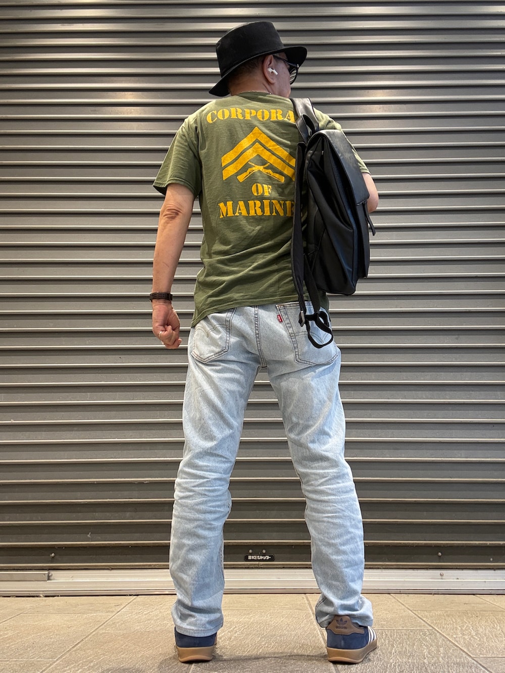ブルー系のデニムパンツ、グリーン系のTシャツ/カットソー、ブラック系のバックパック/リュックを着用したメンズの夏コーディネートの2枚目の写真