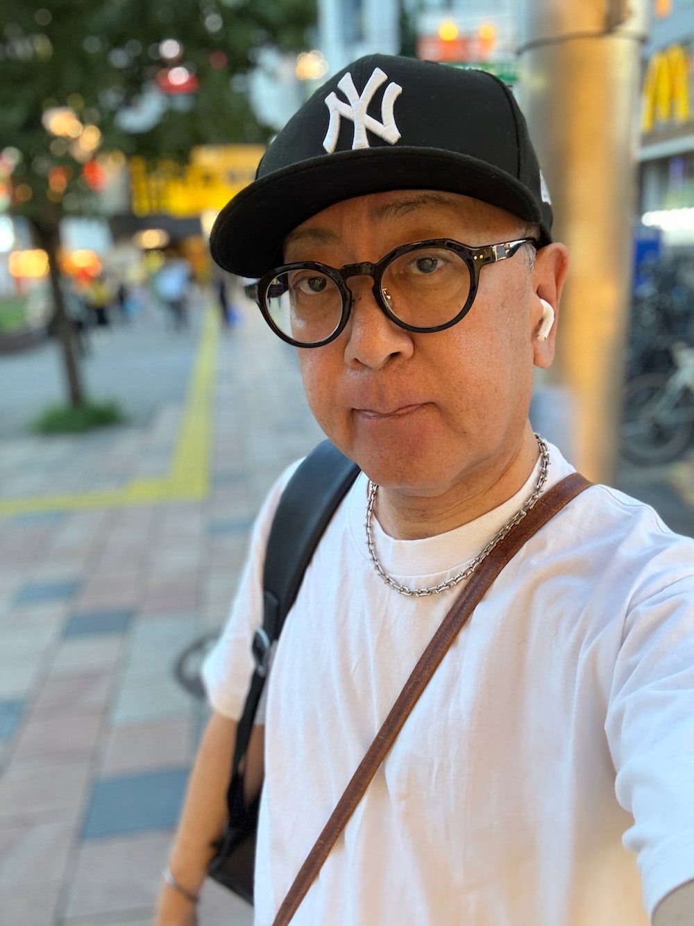 ホワイト系のTシャツ/カットソー、ブルー系のデニムパンツ、ブラウン系のショルダーバッグを着用したメンズの夏コーディネートの2枚目の写真