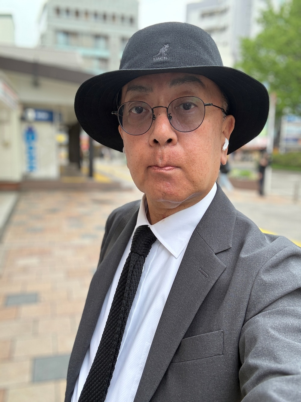 ブラック系のドレスシューズ、ホワイト系のビジネスシャツ、グレー系のテーラードジャケットを着用したメンズの春コーディネートの2枚目の写真