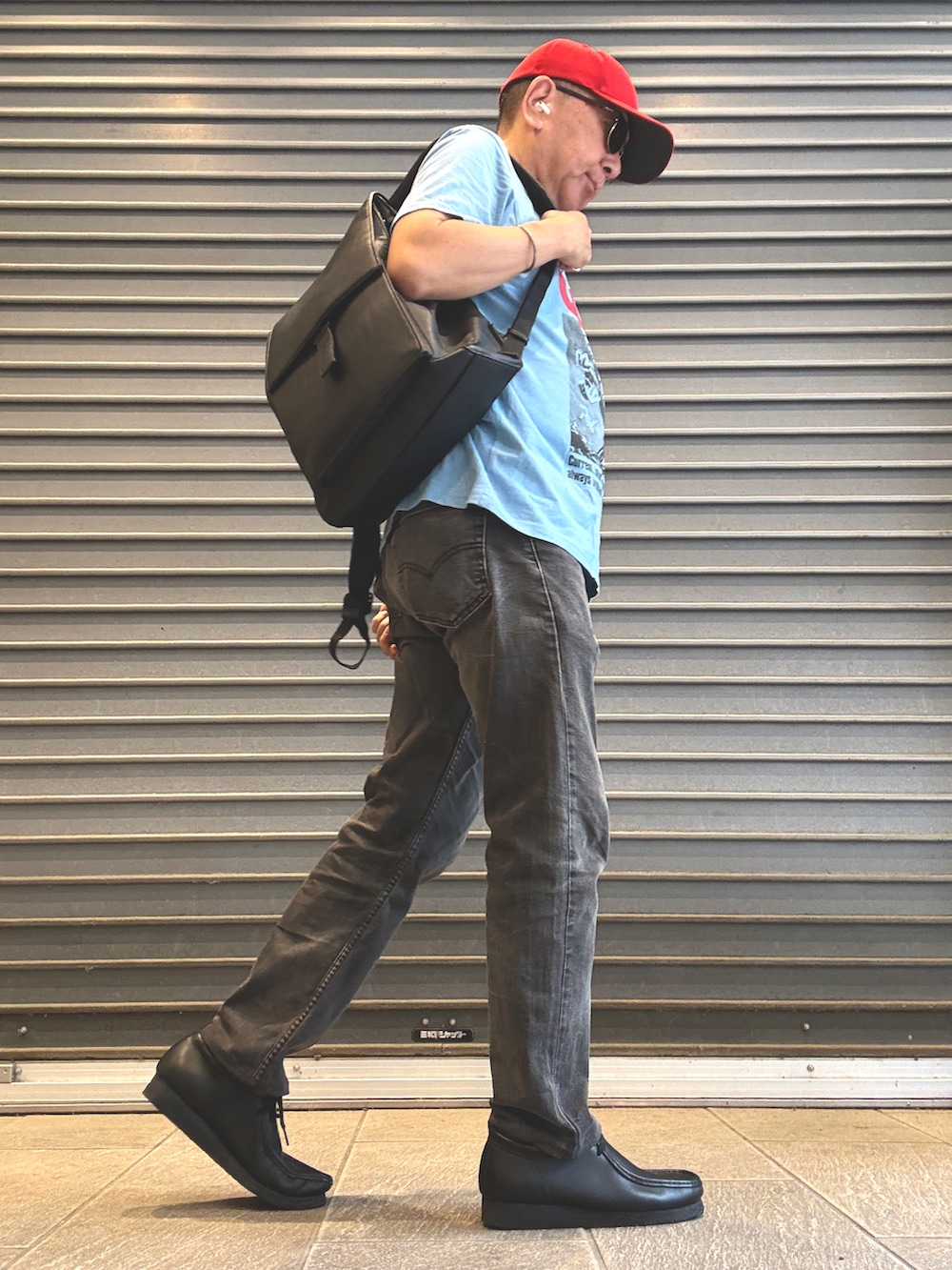 ブラック系のモカシン/デッキシューズ、ブルー系のTシャツ/カットソー、ブラック系のデニムパンツを着用したメンズの秋コーディネートの2枚目の写真