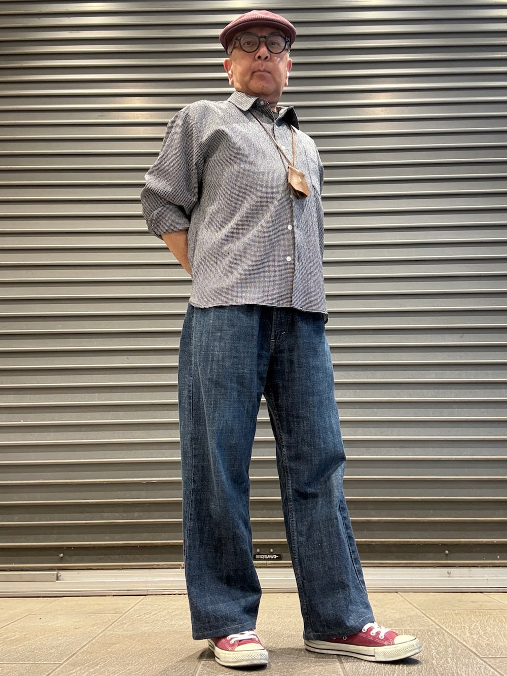 ブルー系のデニムパンツ、ブラック系のシャツ/ブラウス、レッド系のスニーカーを着用したメンズの夏コーディネートの2枚目の写真