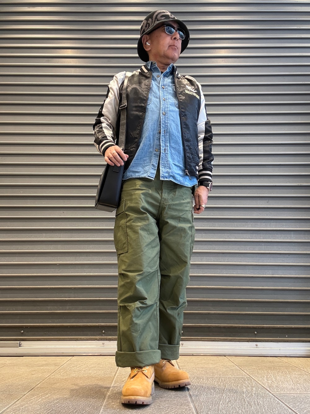 グリーン系のカーゴパンツ、ブラック系のスカジャン、ブルー系のシャツ/ブラウスを着用したメンズの春コーディネートの2枚目の写真