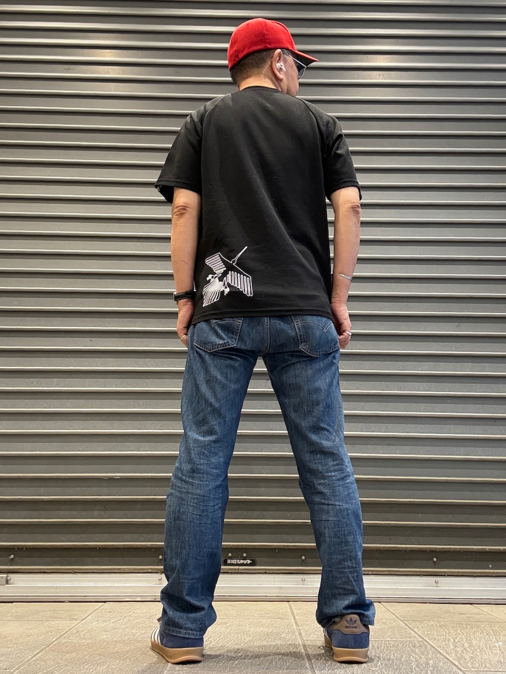 ブルー系のスニーカー、ブラック系のTシャツ/カットソー、ブルー系のデニムパンツを着用したメンズの夏コーディネートの2枚目の写真