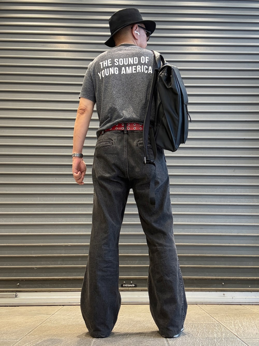 グレー系のデニムパンツ、グレー系のTシャツ/カットソー、ブラック系のバックパック/リュックを着用したメンズの夏コーディネートの2枚目の写真
