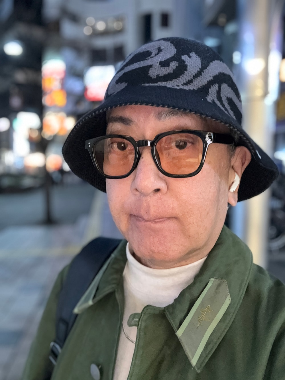 ブラック系のローファー、ベージュ系のTシャツ/カットソー、グリーン系のミリタリージャケットを着用したメンズの春コーディネートの4枚目の写真