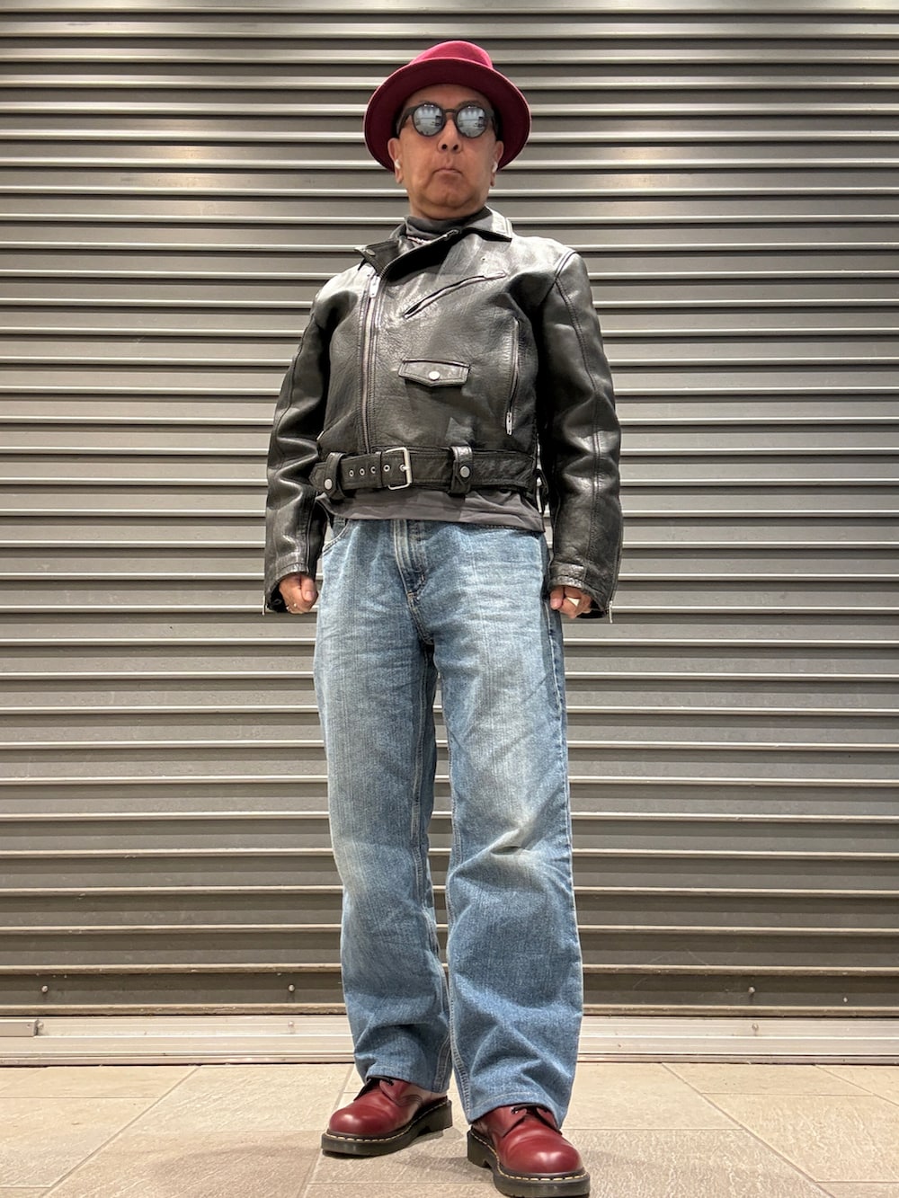 レッド系のブーツ、グレー系のTシャツ/カットソー、ブラック系のライダースジャケットを着用したメンズの秋コーディネートの2枚目の写真