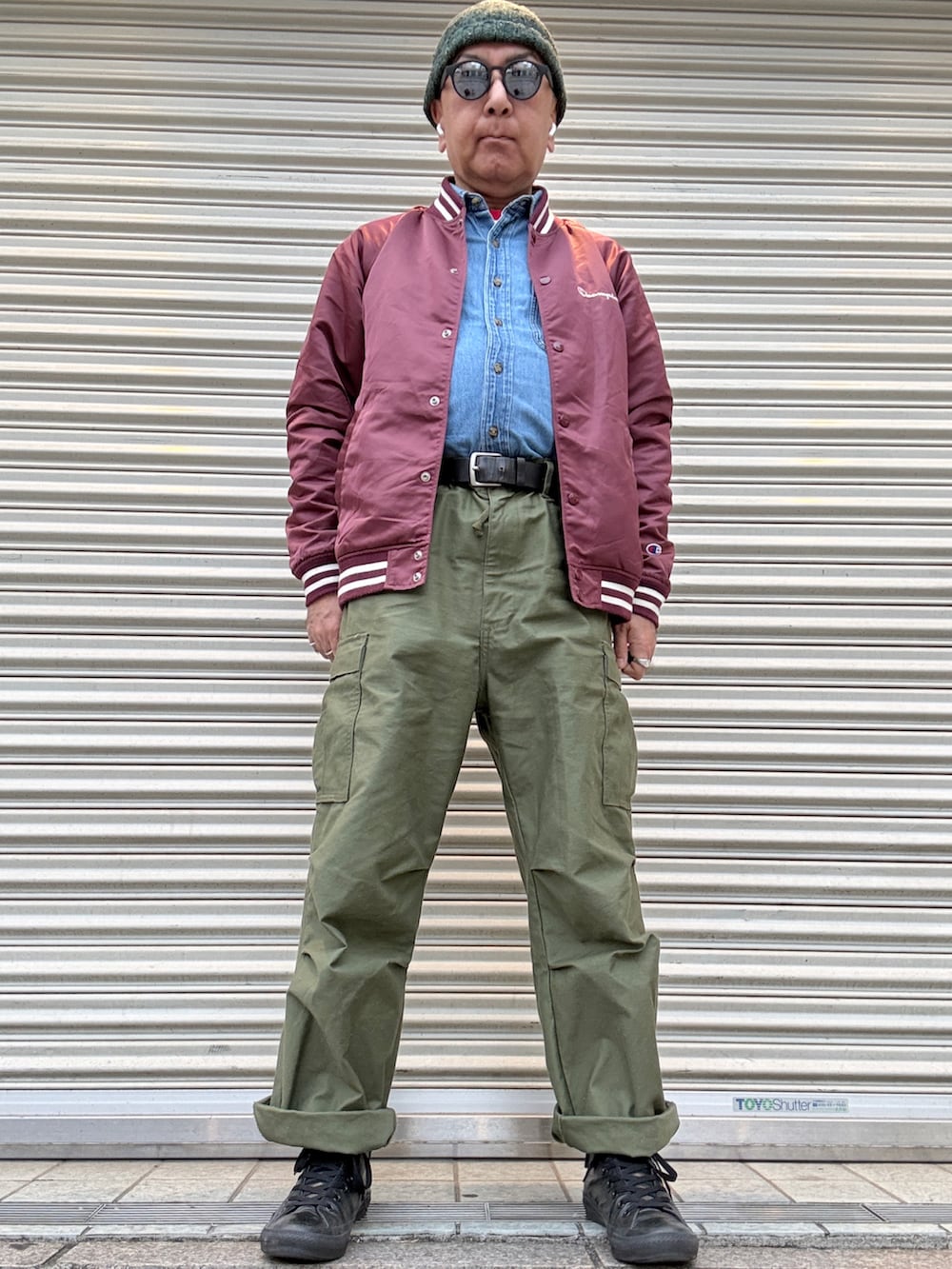 ブルー系のシャツ/ブラウス、レッド系のナイロンジャケット、グリーン系のカーゴパンツを着用したメンズの春コーディネートの2枚目の写真