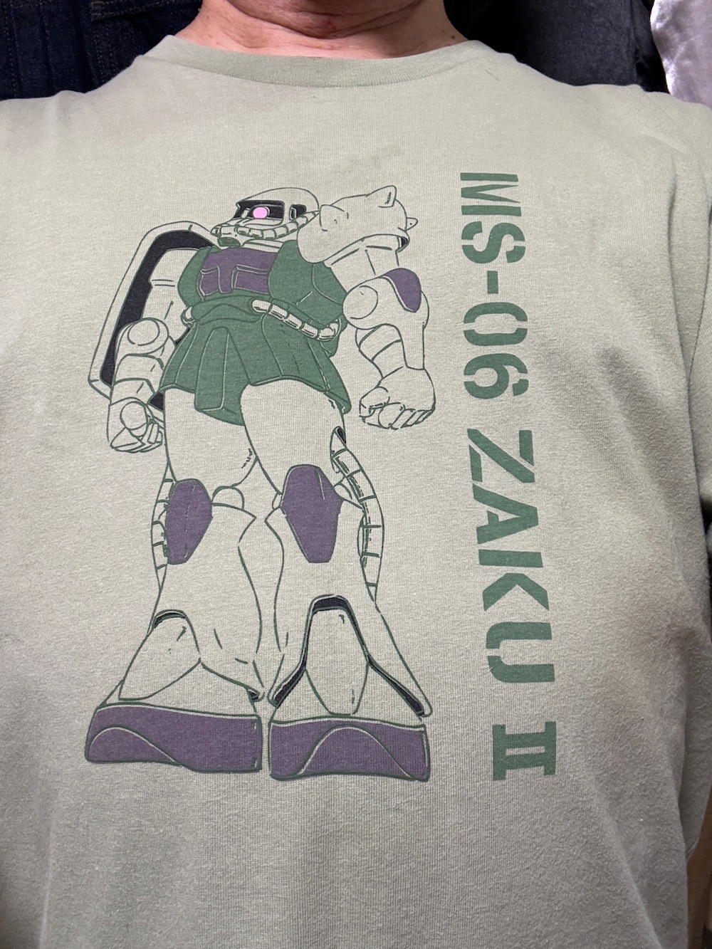 ブルー系のデニムパンツ、グリーン系のTシャツ/カットソー、ブラック系のローファーを着用したメンズの春コーディネートの2枚目の写真