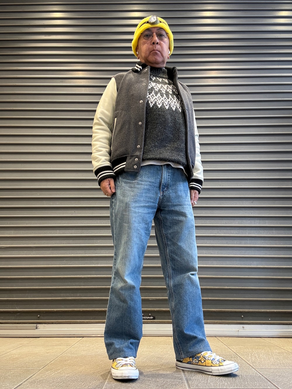 グレー系のニット/セーター、グレー系のスタジャン、ブルー系のデニムパンツを着用したメンズの冬コーディネートの2枚目の写真