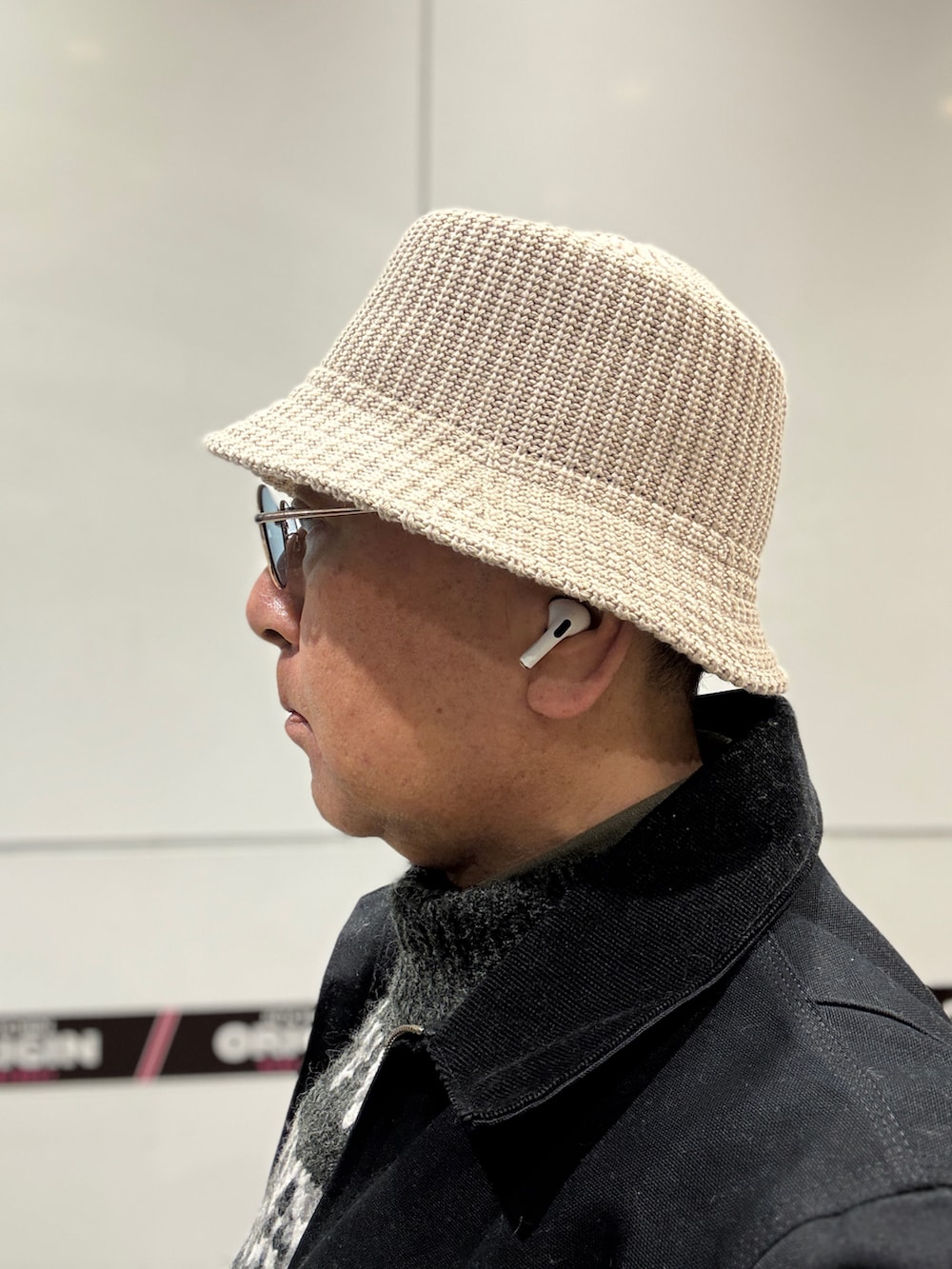 グレー系のニット/セーター、ブラック系のその他アウター、ブルー系のデニムパンツを着用したメンズの冬コーディネートの2枚目の写真