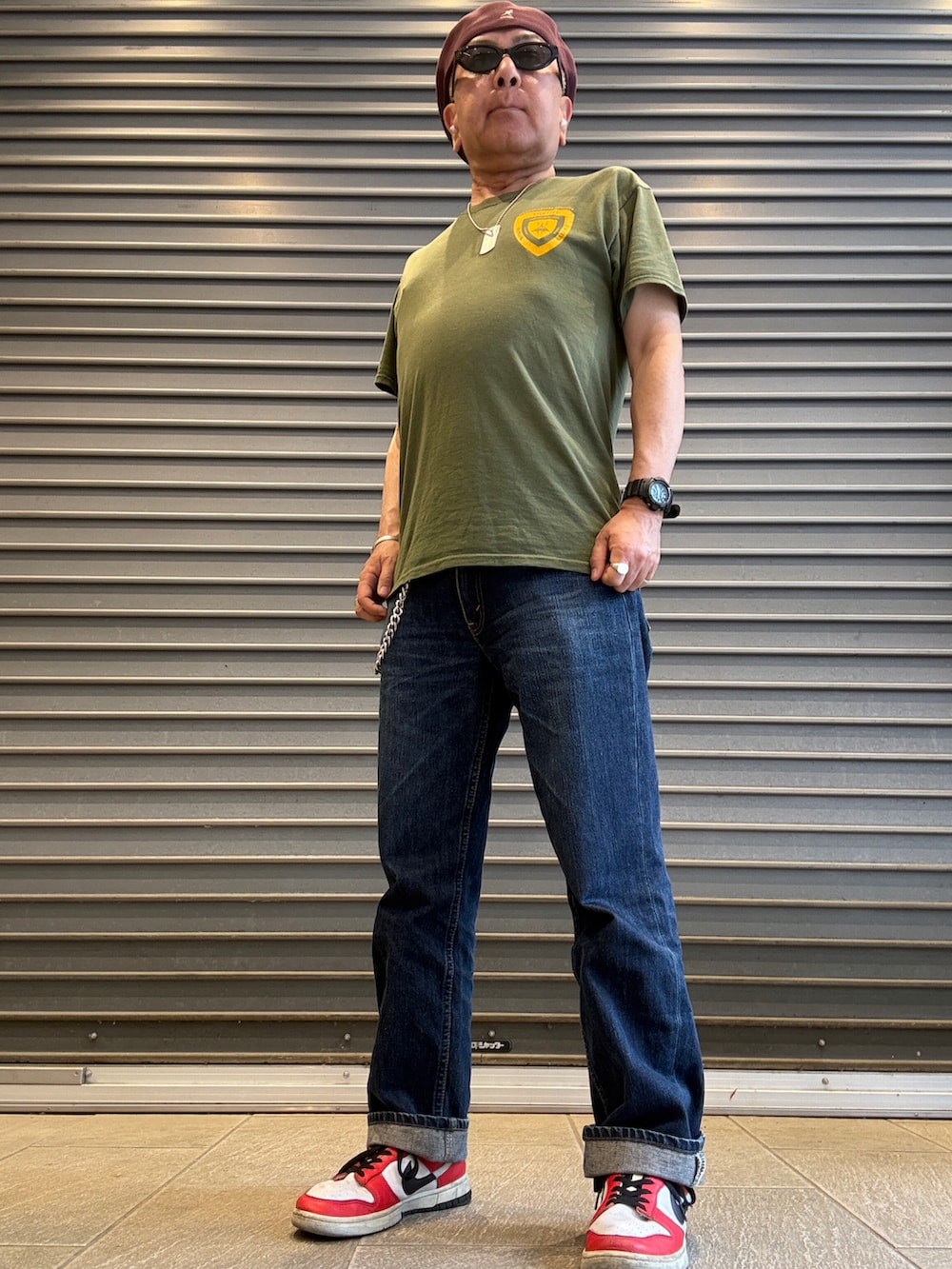 ブルー系のデニムパンツ、グリーン系のTシャツ/カットソー、レッド系のスニーカーを着用したメンズの春コーディネートの3枚目の写真