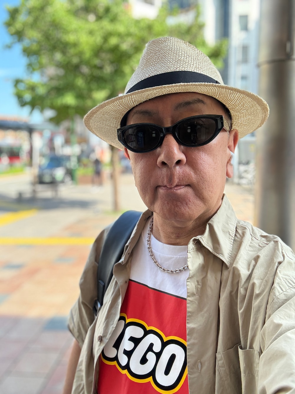 ブラック系のチノパンツ、ホワイト系のTシャツ/カットソー、ベージュ系のシャツ/ブラウスを着用したメンズの夏コーディネートの3枚目の写真