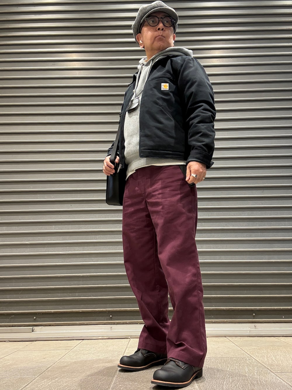 ブラック系のブーツ、ブラック系のその他アウター、レッド系のチノパンツを着用したメンズの春コーディネートの2枚目の写真