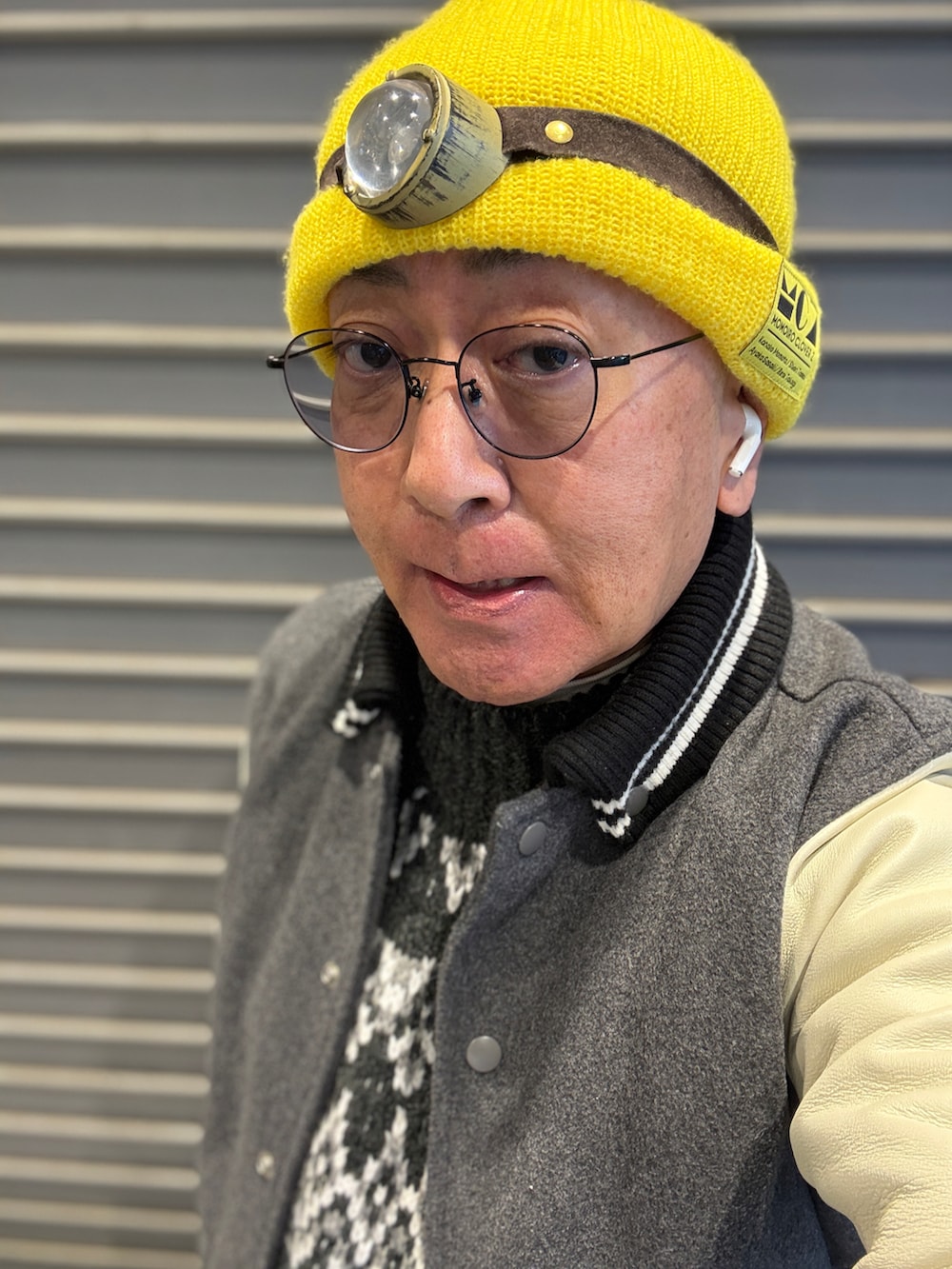 グレー系のニット/セーター、グレー系のスタジャン、ブルー系のデニムパンツを着用したメンズの冬コーディネートの4枚目の写真