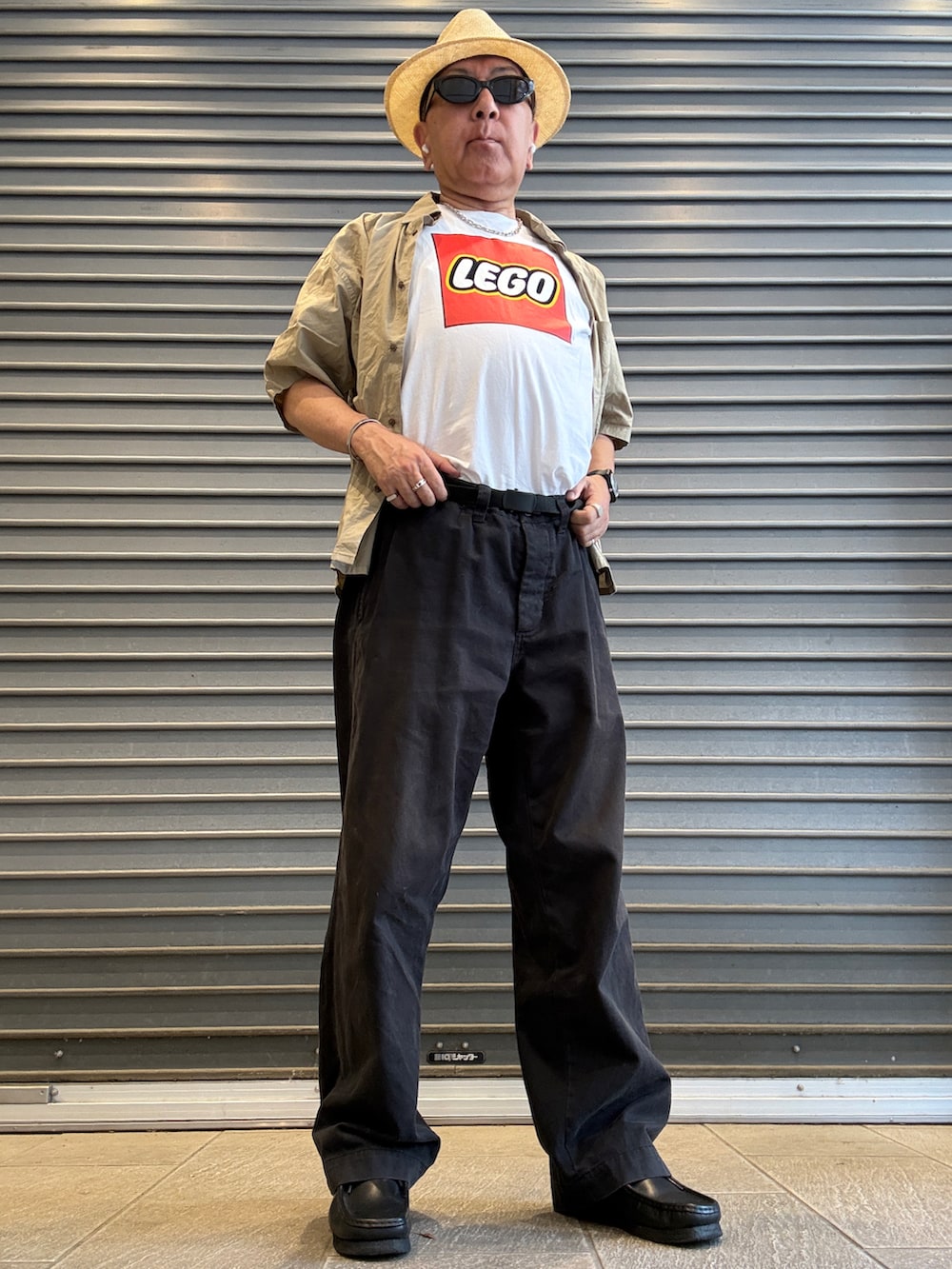 ブラック系のチノパンツ、ホワイト系のTシャツ/カットソー、ベージュ系のシャツ/ブラウスを着用したメンズの夏コーディネートの2枚目の写真