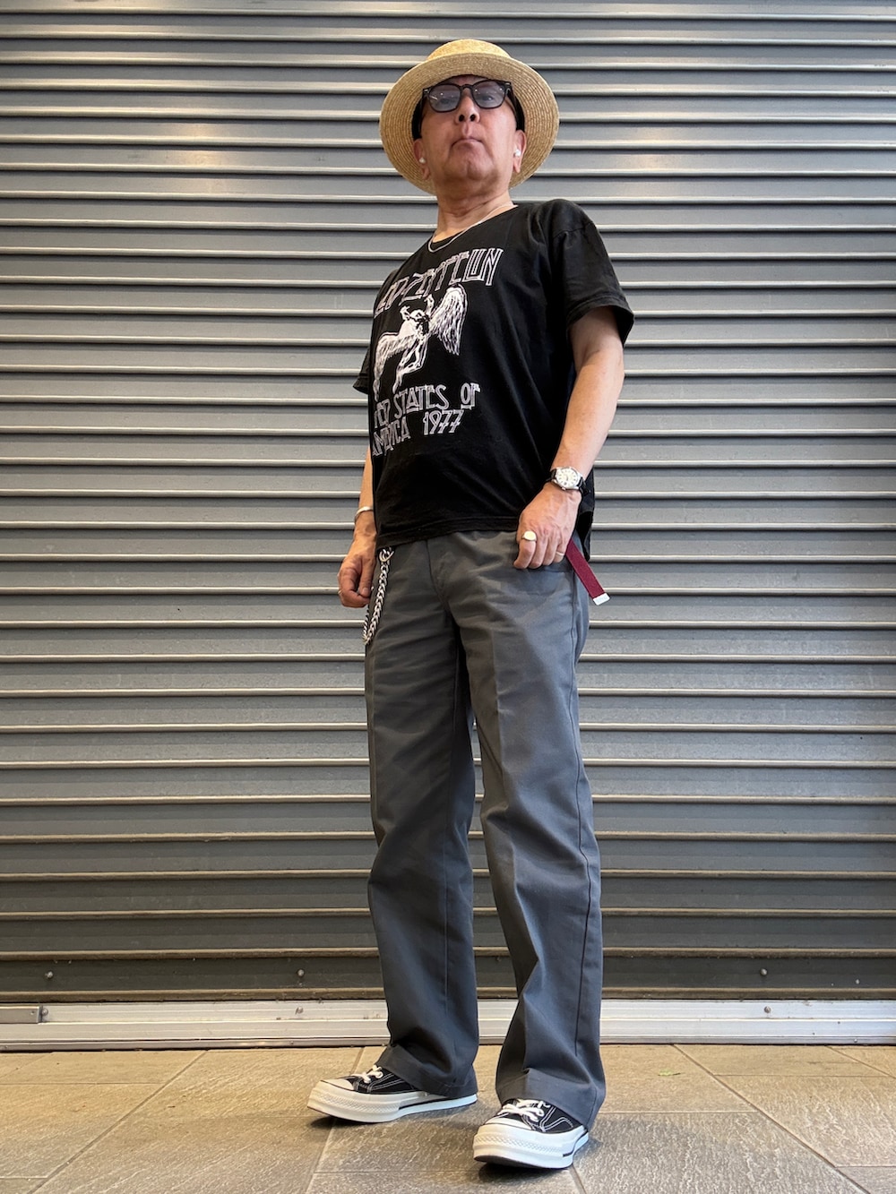 グレー系のチノパンツ、ブラック系のTシャツ/カットソー、ブラック系のスニーカーを着用したメンズの春コーディネートの2枚目の写真