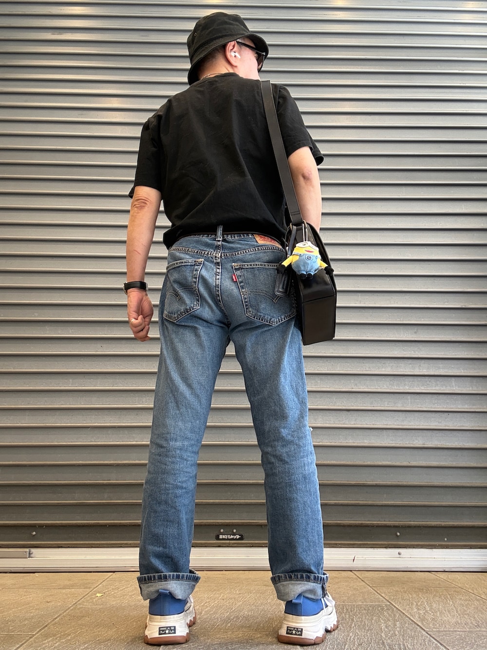 ブルー系のデニムパンツ、ブラック系のTシャツ/カットソー、ブラック系のショルダーバッグを着用したメンズの春コーディネートの2枚目の写真