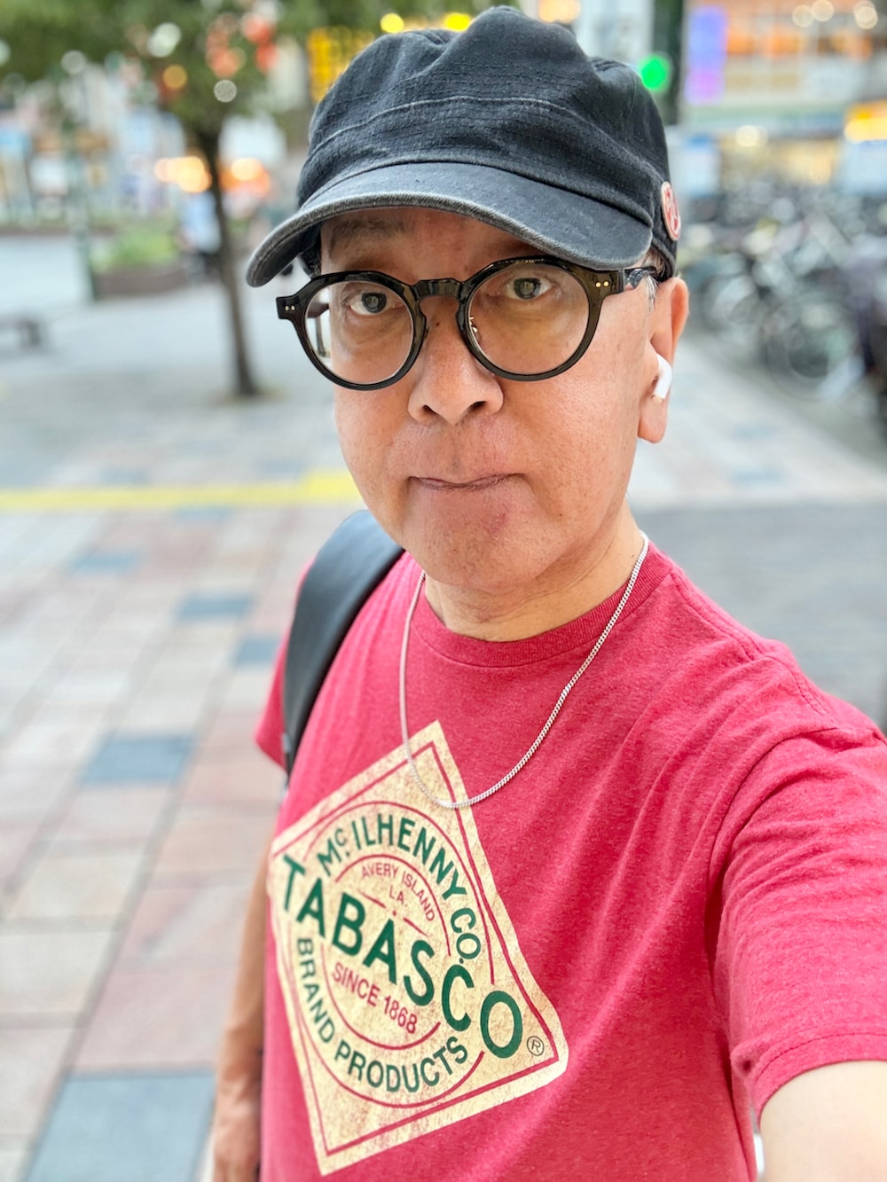 レッド系のTシャツ/カットソー、グリーン系のカーゴパンツ、ブラック系のバックパック/リュックを着用したメンズの夏コーディネートの2枚目の写真