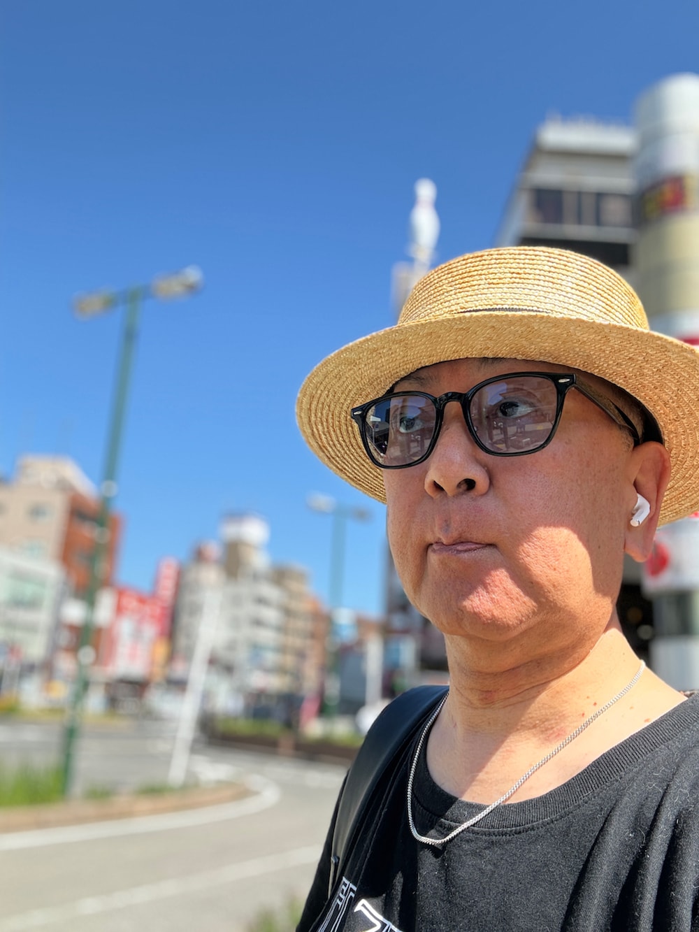 グレー系のチノパンツ、ブラック系のTシャツ/カットソー、ブラック系のスニーカーを着用したメンズの春コーディネートの3枚目の写真