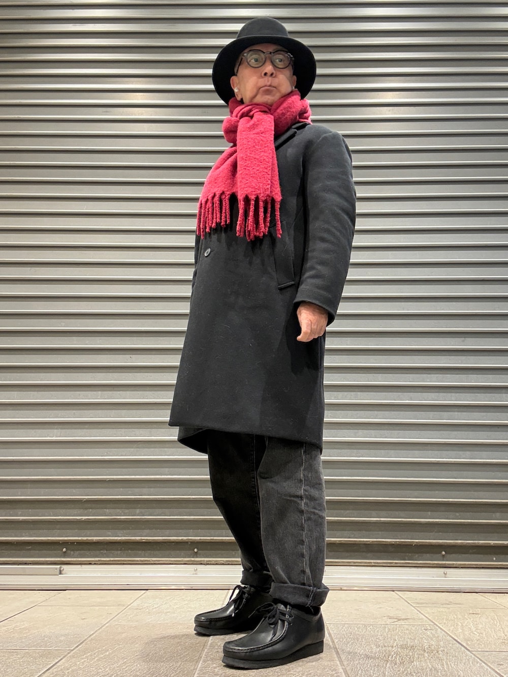 ブラック系のチェスターコート、ホワイト系のTシャツ/カットソー、グレー系のニット/セーターを着用したメンズの冬コーディネートの2枚目の写真