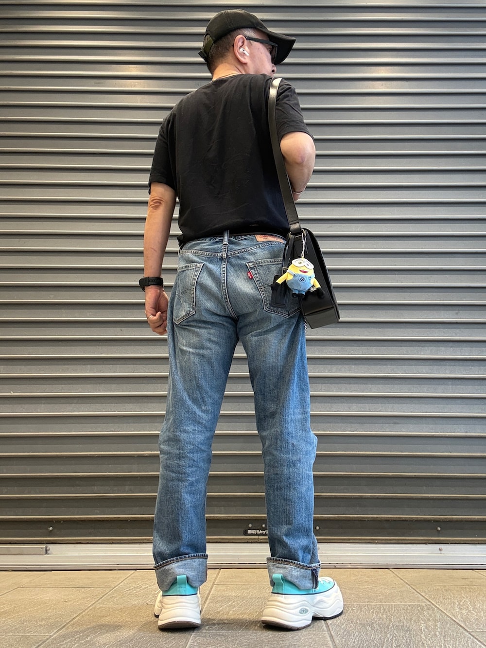 ブラック系のTシャツ/カットソー、ブラック系のショルダーバッグ、ブルー系のスニーカーを着用したメンズの夏コーディネートの2枚目の写真