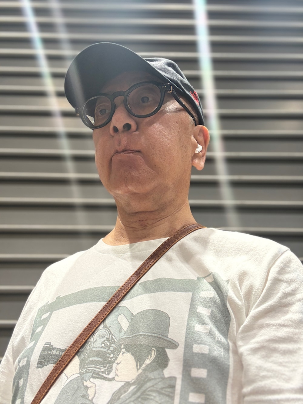 ホワイト系のTシャツ/カットソー、ブルー系のデニムパンツ、ブラウン系のショルダーバッグを着用したメンズの夏コーディネートの2枚目の写真