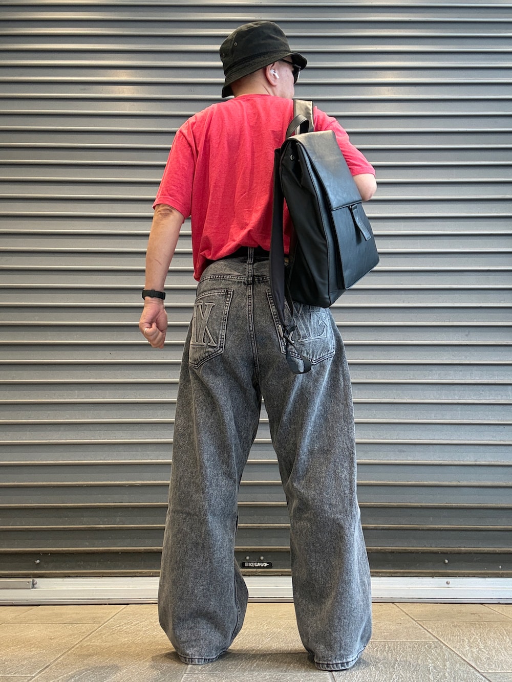 ブラック系のデニムパンツ、レッド系のTシャツ/カットソー、ブラック系のバックパック/リュックを着用したメンズの夏コーディネートの3枚目の写真