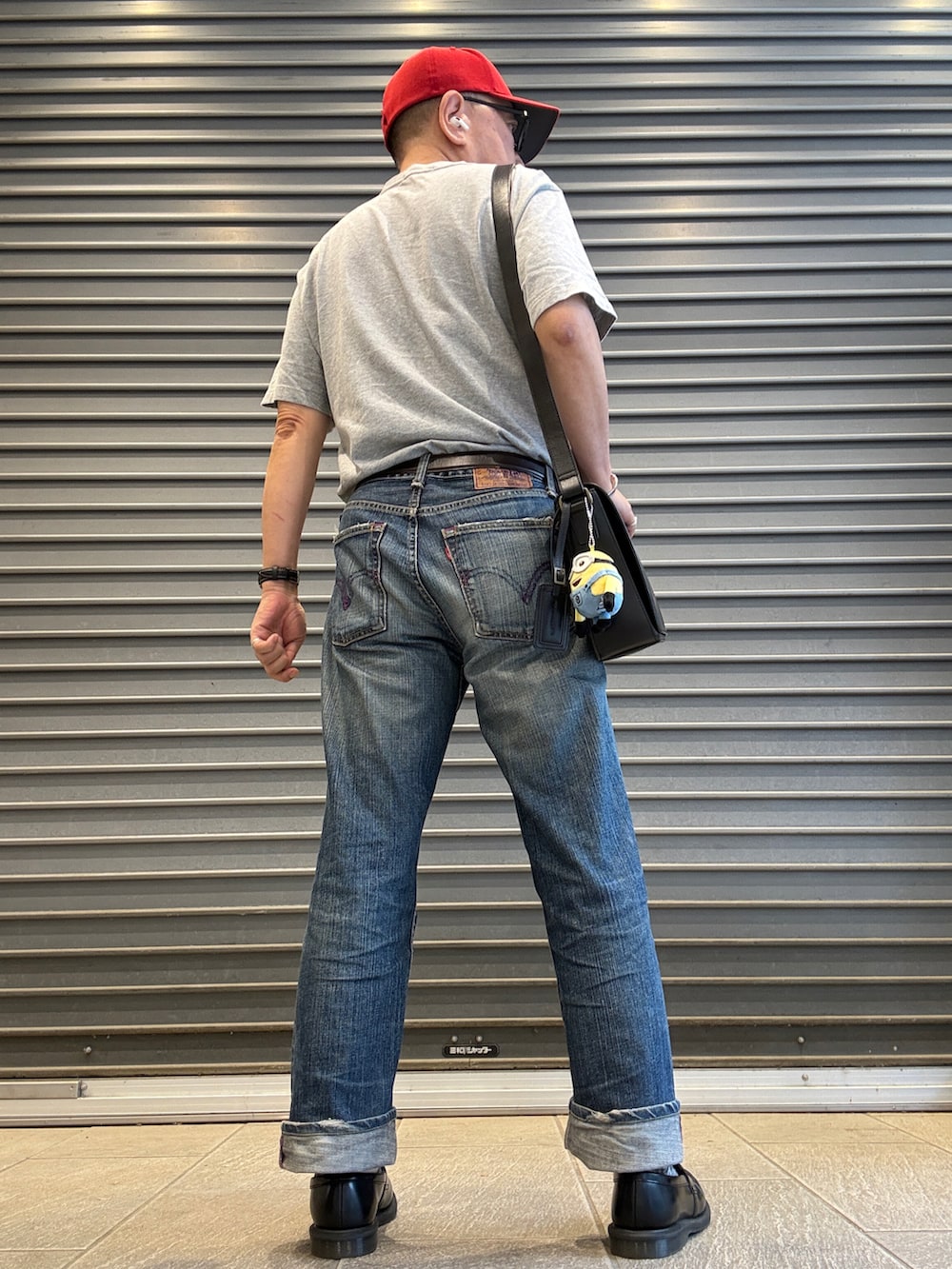 ブルー系のデニムパンツ、グレー系のTシャツ/カットソー、ブラック系のショルダーバッグを着用したメンズの夏コーディネートの3枚目の写真