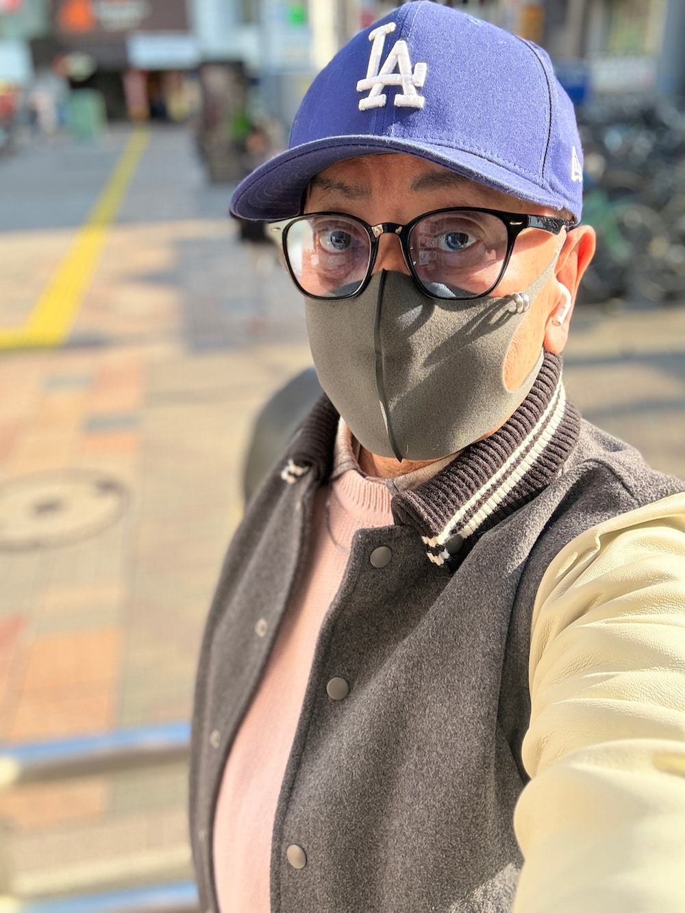 グレー系のスタジャン、ピンク系のニット/セーター、ブラック系のシャツ/ブラウスを着用したメンズの春コーディネートの2枚目の写真