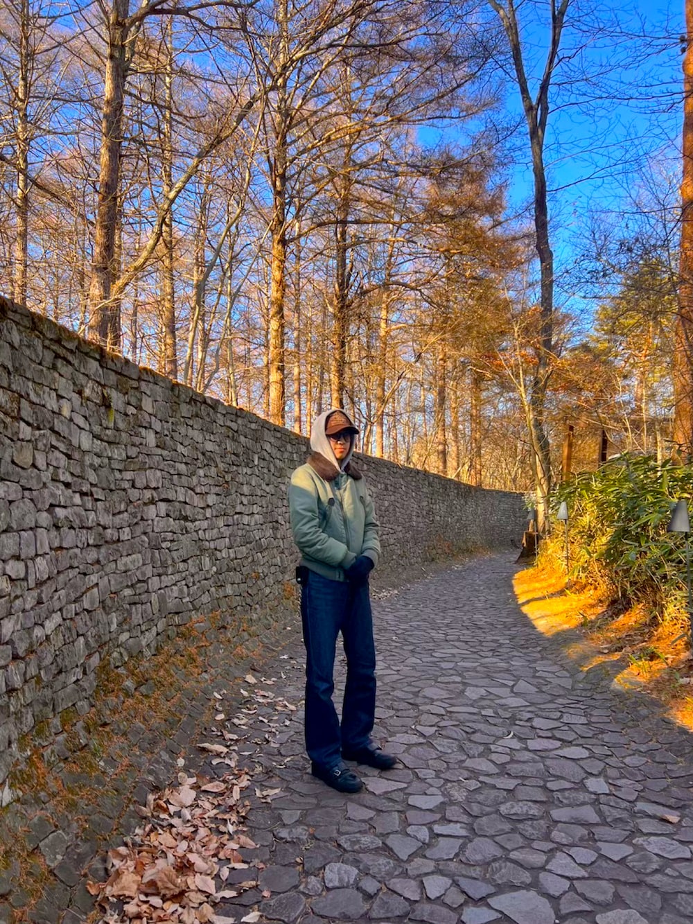 グリーン系のミリタリージャケット、ブルー系のデニムパンツ、ブラック系のスニーカーを着用したメンズの冬コーディネートの2枚目の写真