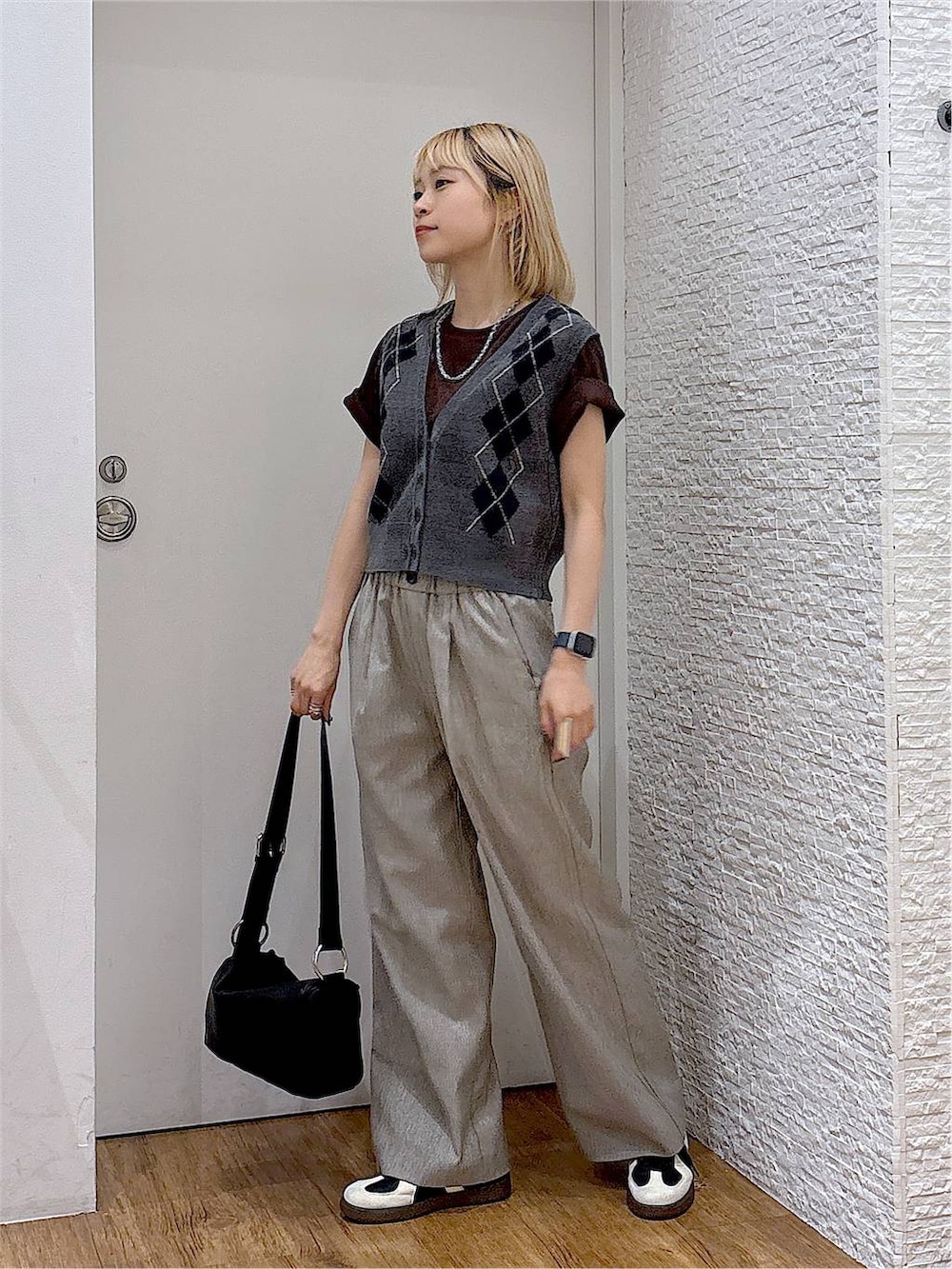 グレー系のベスト、ブラック系のスニーカー、ブラウン系のTシャツ/カットソーを着用したレディースの夏コーディネートの2枚目の写真